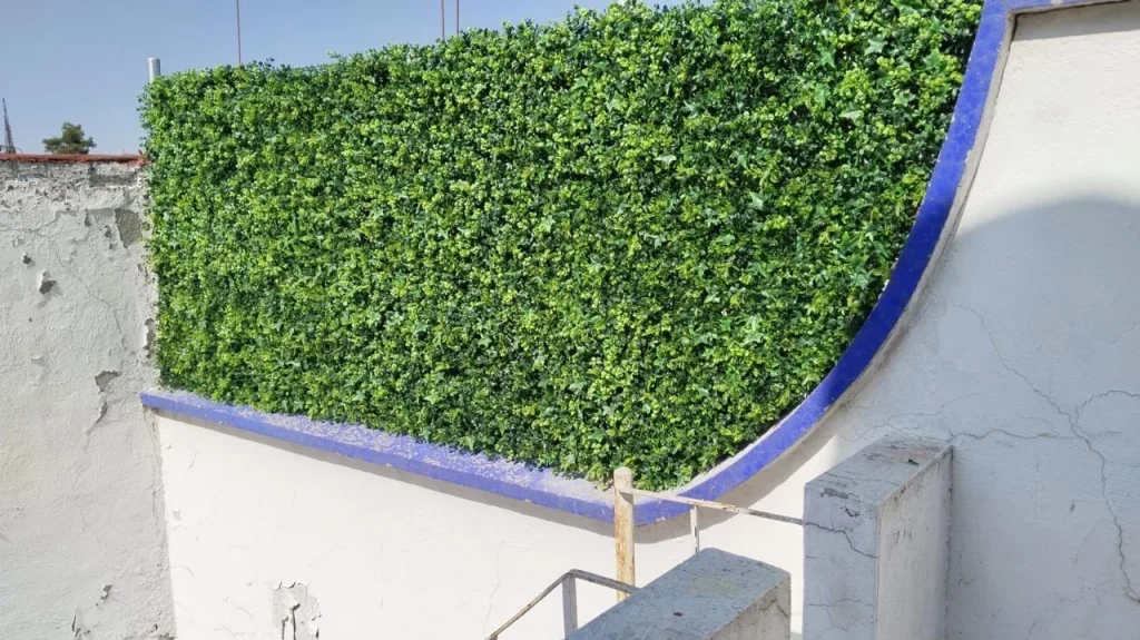 Panel de follaje artificial verde instalado sobre un muro.