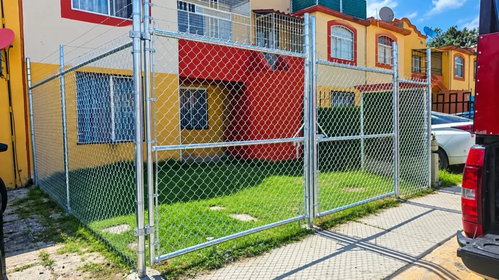 Puerta de acceso y cercado de malla ciclónica en un conjunto residencial.
